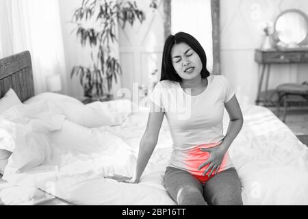 Asiatische Frau, Die An Unterbauch Schmerzen Zu Hause, Schwarz-Weiß Stockfoto