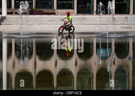 Ein Kind mit einer Spiderman Gesichtsmaske radelt nach der Einführung von Maßnahmen, um das Land aus der Blockierung zu bringen, durch den Centenary Square in Birmingham. Stockfoto