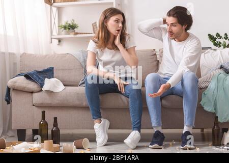 Schockiert Millennial Paar Blick Auf Ihre Chaotisch Wohnung Nach Party Stockfoto