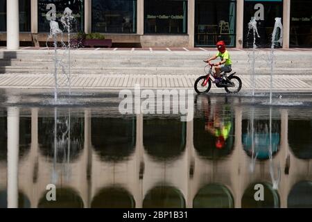 Ein Kind mit einer Spiderman Gesichtsmaske radelt nach der Einführung von Maßnahmen, um das Land aus der Blockierung zu bringen, durch den Centenary Square in Birmingham. Stockfoto