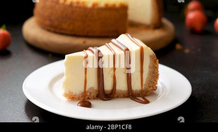 Käsekuchen mit Karamellsauce auf schwarzem Hintergrund. Leckerer selbstgemachter Karamell-Käsekuchen Stockfoto