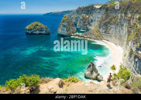 Der Reisende Mann steht auf dem Gipfel des Berges Blick auf das Meer und die Felsen. Reise- und Active Lifestyle Konzept. Abenteuer und Reise auf Bali, Indonesien. Stockfoto