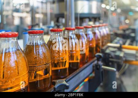Förderband, Saft in Flaschen auf Getränkeanlage oder Fabrikinnenraum, industrielle Produktionslinie, selektiver Fokus. Stockfoto