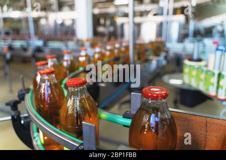 Förderband, Saft in Flaschen auf Getränkeanlage oder Fabrikinnenraum, industrielle Produktionslinie, selektiver Fokus. Stockfoto