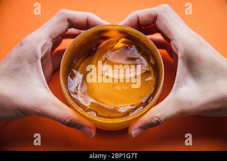 Beauty-Pflegeprodukte und Herz mit Händen, Liebe Zeichen auf hellem orangefarbenen Hintergrund, Gesichtsbehandlung Artikel, Schnecke Lotion Stockfoto