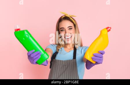 Sauberes Zuhause. Glückliche Hausfrau in Gummihandschuhen hält Reinigungsflaschen in den Händen Stockfoto