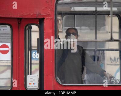 Belgrad, Serbien - 15. Mai 2020: Frau mit chirurgischen Gesichtsmasken während der Fahrt in einer roten Straßenbahn, von außen Stockfoto