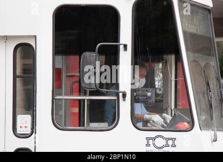 Belgrad, Serbien - 15. Mai 2020: Straßenbahnfahrer, die von außen in einer weißen Straßenbahn operativ Gesichtsmasken und Handschuhe tragen Stockfoto