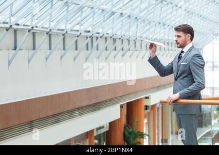 Junger Geschäftsmann wirft ein Papierflugzeug im Bürogebäude Stockfoto