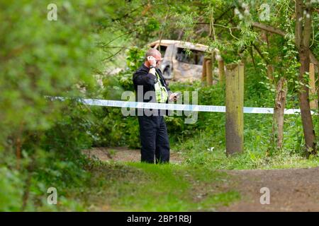 Ein Tatort Offizier bewacht ein ausgebranntes Fahrzeug in Shillington, wo der Fahrer des Unfalles das Fahrzeug floh. Stockfoto