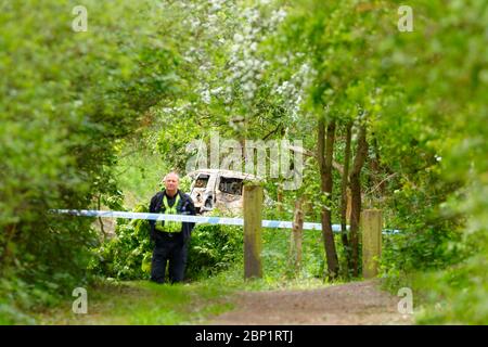 Ein Tatort Offizier bewacht ein ausgebranntes Fahrzeug in Shillington, wo der Fahrer des Unfalles das Fahrzeug floh. Stockfoto