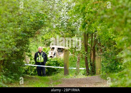 Ein Tatort Offizier bewacht ein ausgebranntes Fahrzeug in Shillington, wo der Fahrer des Unfalles das Fahrzeug floh. Stockfoto