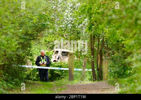 Ein Tatort Offizier bewacht ein ausgebranntes Fahrzeug in Shillington, wo der Fahrer des Unfalles das Fahrzeug floh. Stockfoto