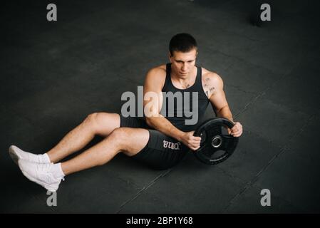 Muskulöse starke Mann tun russischen Twist Übung mit Gewicht von Langhantel. Stockfoto