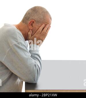 Beschämt und deprimiert Mann versteckt sein Gesicht mit den Händen an einem Tisch. Nahaufnahme Bild isoliert auf weißem Hintergrund. Stockfoto