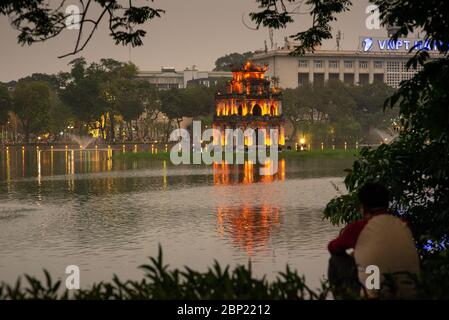 Unkenntlich Mann, der Hoan Kiem See und der Schildkrötenturm, am frühen Abend, Hanoi, Vietnam Stockfoto