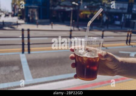 mans Hand hält Eiskaffeetasse an sonnigen heißen Tag Stockfoto