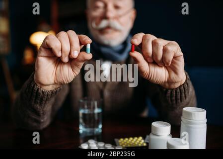 Ein älterer Mann hält Pillen in seinen Händen Stockfoto