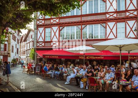 Saint Jean de Luz, französisches Baskenland, Frankreich - 13. Juli 2019: Die Leute sitzen auf der Außenterrasse des Cafe Majestic im Place Louis, 14:00 Uhr Stockfoto