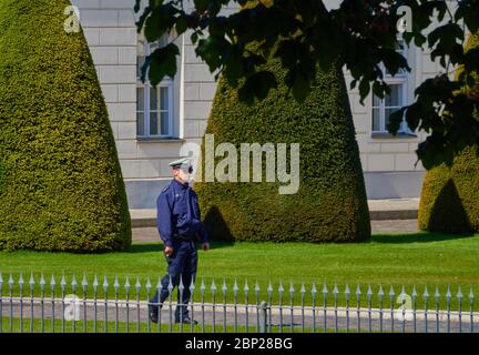 Berlin, 6. Mai 2020: Deutscher Polizist in blauer Uniform mit weißer Spitze geht im Garten vor dem Bundespräsidenten-Schloss p Stockfoto