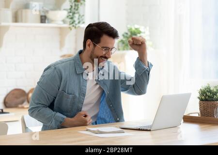 Aufgeregt Mann fühlen euphorisch Lesen gute Nachrichten auf dem Laptop Stockfoto