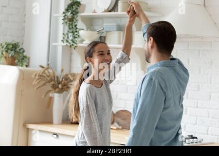 Fröhliches junges Paar tanzt in der modernen Küche zu Hause Stockfoto