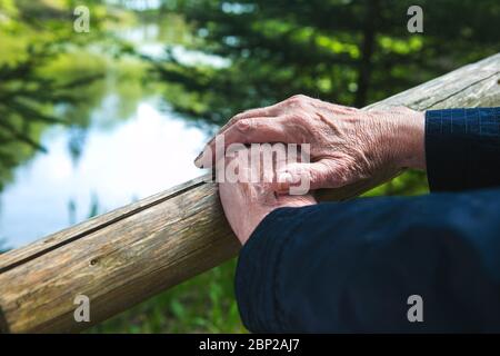 Nahaufnahme der Hände alter Frauen, die an einem Geländer in der Natur ruhen Stockfoto