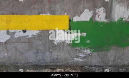 Verwitterte raue Zementwand mit rechteckigen Flecken von gelben und grünen Flecken. Abstrakter Hintergrund der Baureparaturindustrie Stockfoto