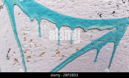 Striche von hellblauer Farbe auf weißer Stuckwandoberfläche. Nahaufnahme von blauer tropfender Farbe. Abstrakt gemalten Hintergrund mit Copy-Raum Stockfoto