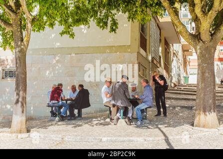 Touristenfrau, die Fotos von portugiesischen Männern beim Kartenspielen in der Nähe des Wohnhauses fotografiert. Stockfoto