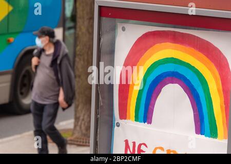 Montreal, CA - 16. Mai 2020: Mann mit Gesichtsmaske zum Schutz vor COVID-19 zu Fuß in der Nähe Regenbogenzeichnung Stockfoto