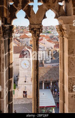 Trogir, Kroatien - 8. September 2019: Blick vom Turm durch das mittelalterliche Fenster auf den Altstadtplatz und den Uhrturm von Trogir Stockfoto