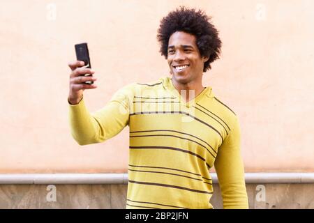 Black man mit Afro Hair und Kopfhörern über Smartphone. Stockfoto