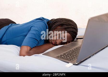 Frau müde von der Arbeit, schläft auf dem Bett vor einem Laptop. Hypnotism Werbekonzept, Frau, die viel zu viel arbeitet Stockfoto