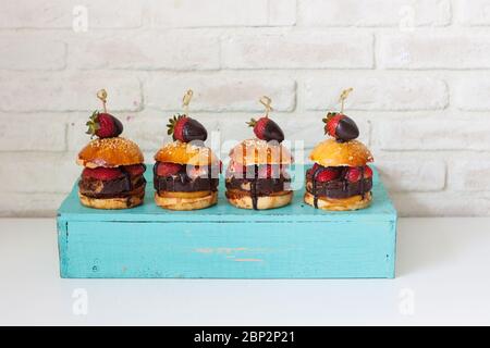 Süße Burger mit Brioche-Brötchen, Schokobrownie-Schicht, frischen Erdbeeren und geschmolzener Schokoladensauce. Weißer Hintergrund. Stockfoto