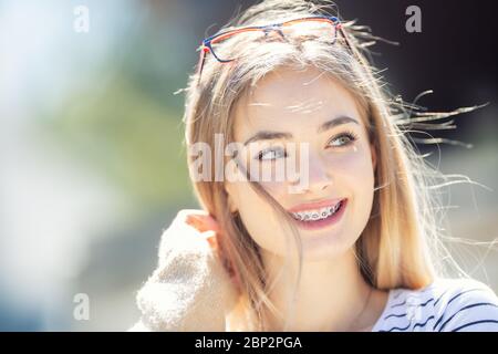 Schöne junge blonde Mädchen trägt Zahnspange, lächelnd und auf die Seite. Stockfoto