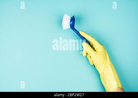 Hand in einem Gummihandschuh mit Pinsel, blauer Hintergrund. Stockfoto