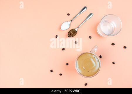 Tasse mit Dalgona Kaffee auf beigem Hintergrund mit Kaffeebohnen. Stockfoto