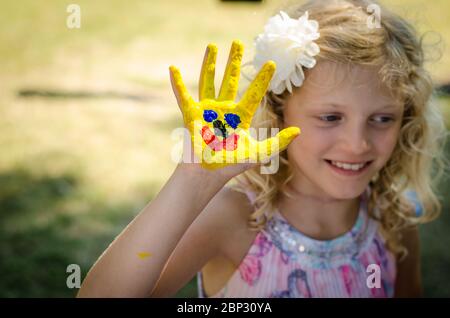 Glücklich lächelndes Kind mit buntem Bild auf ihrer Hand und Finger Stockfoto