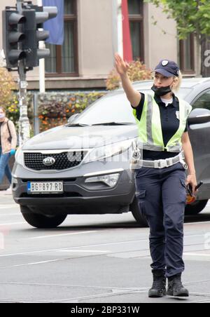 Belgrad, Serbien - 15. Mai 2020: Verkehrspolizistin im Dienst, die an der Kreuzung steht, während Fahrzeuge, die sich in Bewegung bewegen, verschwimmen Stockfoto