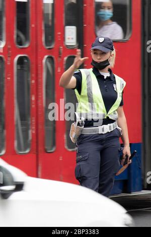 Belgrad, Serbien - 15. Mai 2020: Verkehrspolizistin im Dienst, die an der Kreuzung steht, während Fahrzeuge, die sich in Bewegung bewegen, verschwimmen Stockfoto