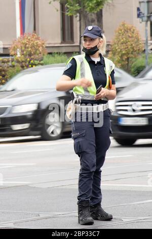 Belgrad, Serbien - 15. Mai 2020: Verkehrspolizistin im Dienst, die an der Kreuzung steht, während Fahrzeuge, die sich in Bewegung bewegen, verschwimmen Stockfoto