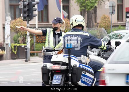 Belgrad, Serbien - 15. Mai 2020: Verkehrspolizistin und Motorpolizist im Dienst, stehend an der Kreuzung und sprechend Stockfoto