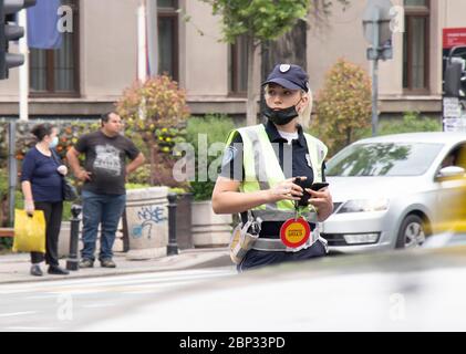 Belgrad, Serbien - 15. Mai 2020: Polizistin im Dienst, die am Schnittpunkt mit dem Verkehr in Bewegung steht, verschwimmt Stockfoto