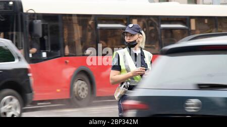 Belgrad, Serbien - 15. Mai 2020: Verkehrspolizistin im Dienst, die an der Kreuzung steht, während Fahrzeuge, die sich in Bewegung bewegen, verschwimmen Stockfoto