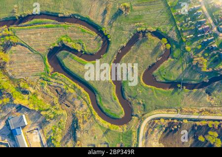 Luftlandschaft von gewundenen kleinen Fluss, Bach im grünen Feld, oben Abend Sonnenuntergang Blick Wiese Stockfoto