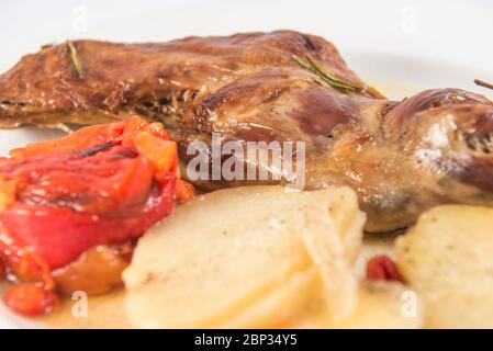 Gebackene Ziegenkeule, mit gebackenen Kartoffeln und gerösteten roten Paprika. Stockfoto