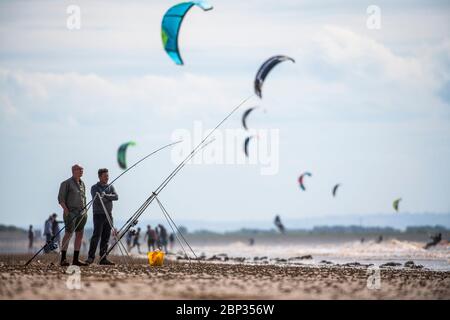 Fischer am Strand von Weston-super-Mare mit Kitesurfern im Hintergrund wie Coronavirus Beschränkungen in England gelockert werden. Stockfoto