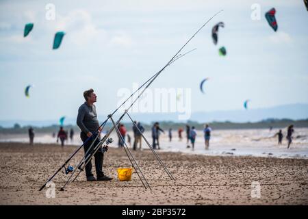 Fischer am Strand von Weston-super-Mare mit Kitesurfern im Hintergrund wie Coronavirus Beschränkungen in England gelockert werden. Stockfoto