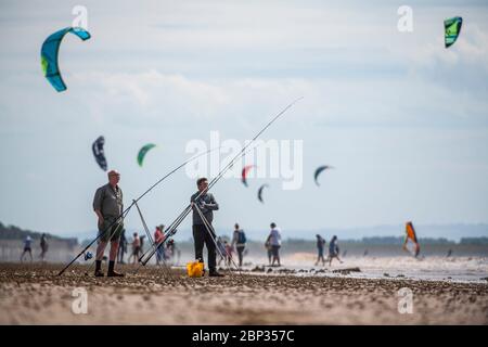 Fischer am Strand von Weston-super-Mare mit Kitesurfern im Hintergrund wie Coronavirus Beschränkungen in England gelockert werden. Stockfoto